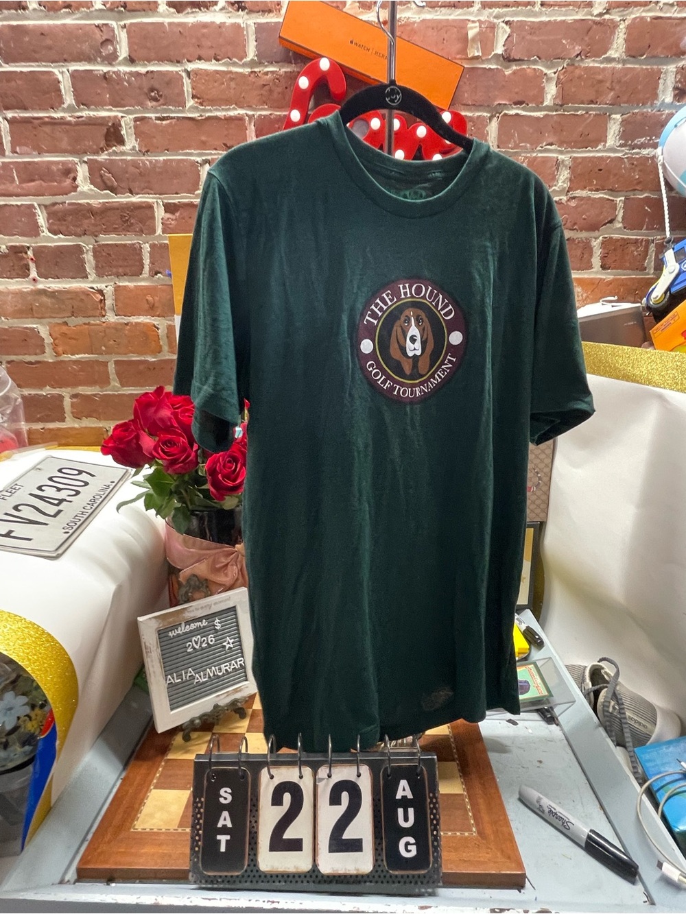 dark green graphic t-shirt features a round "The Hound Golf Tournament" logo on